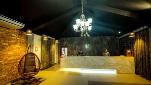 A reception area with a marble counter, a hanging chair, and a chandelier. - Shaira Garden Resort (Bandar)