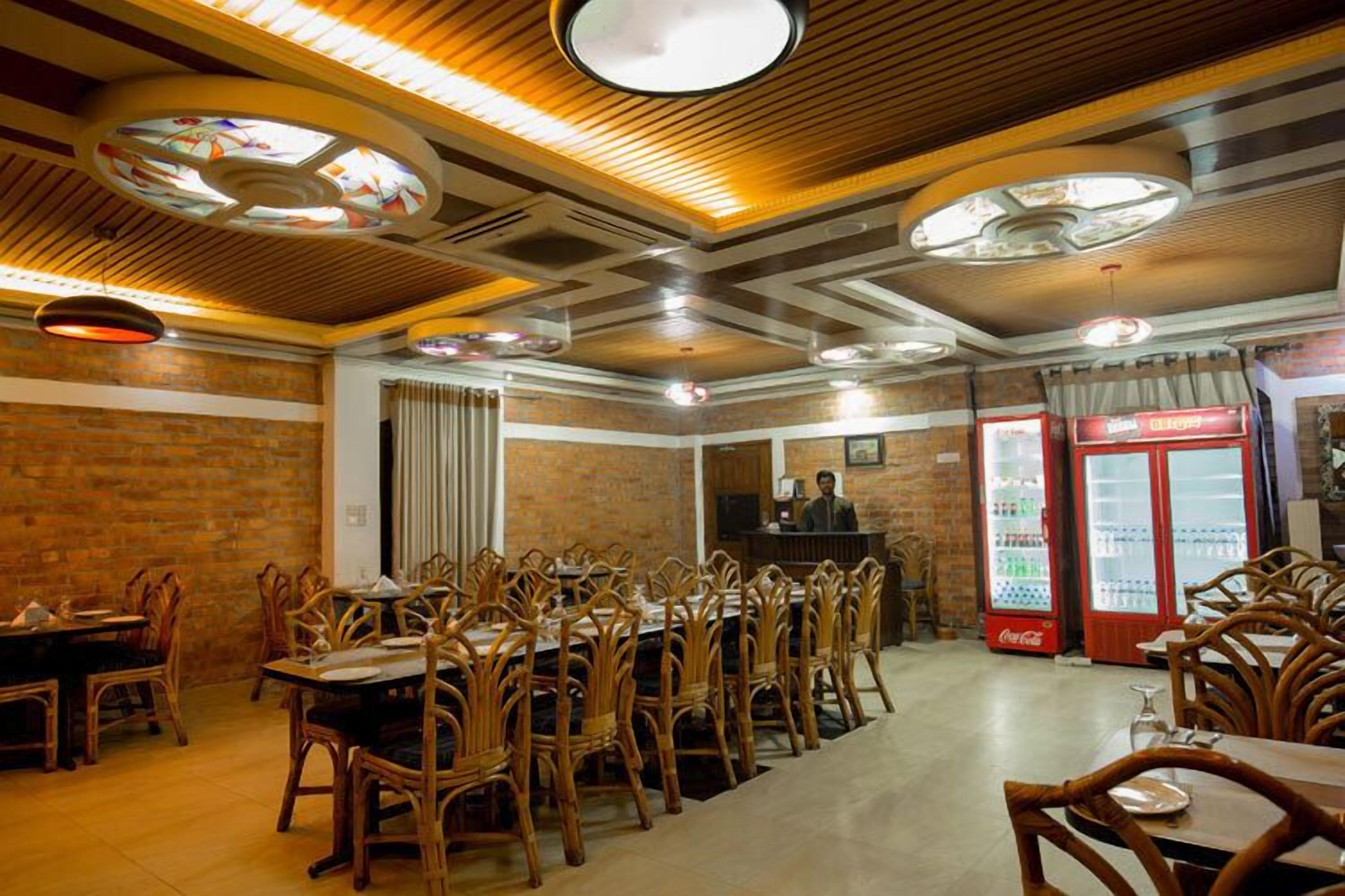 A restaurant with brick walls, wooden tables and chairs, and two Coca-Cola refrigerators.