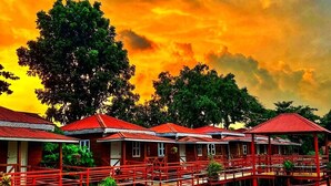 A row of red-roofed wooden structures on stilts over water, with a sunset sky in the background. - Shaira Garden Resort (Bandar)