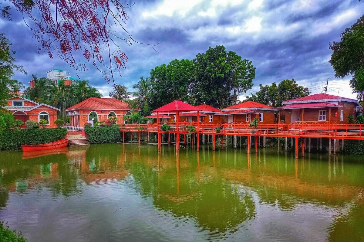 A waterfront property with multiple red-roofed buildings, a dock, and lush greenery.