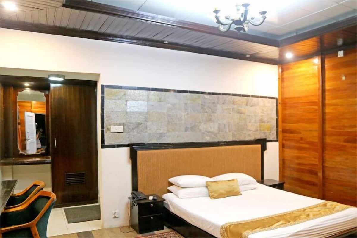 A bedroom with a bed, a nightstand, a desk, and a mirror.