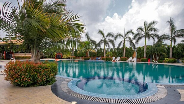 A swimming pool with a circular hot tub, surrounded by palm trees and lounge chairs. - Shaira Garden Resort (Bandar)