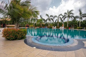 A swimming pool with a circular hot tub, surrounded by palm trees and lounge chairs. - Shaira Garden Resort (Bandar)