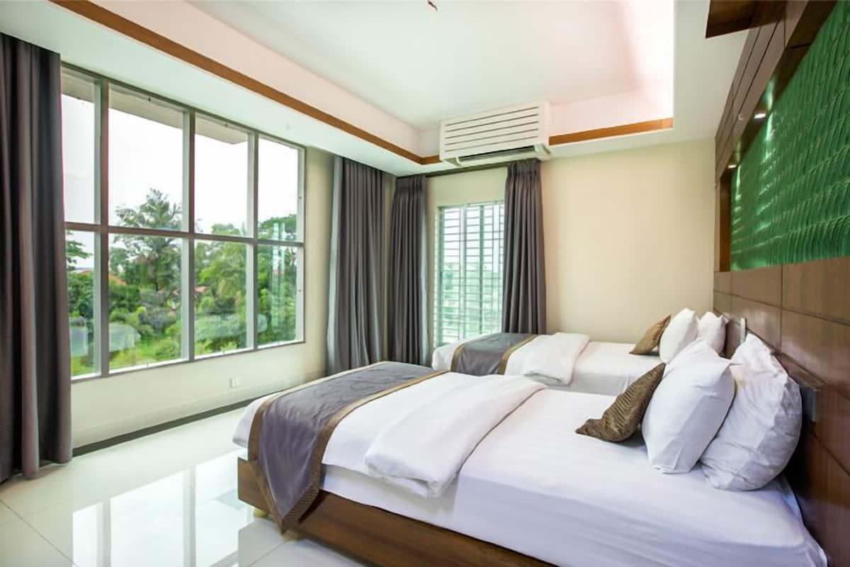 A hotel room with two beds, large windows, an air conditioning unit, and a view of greenery outside.