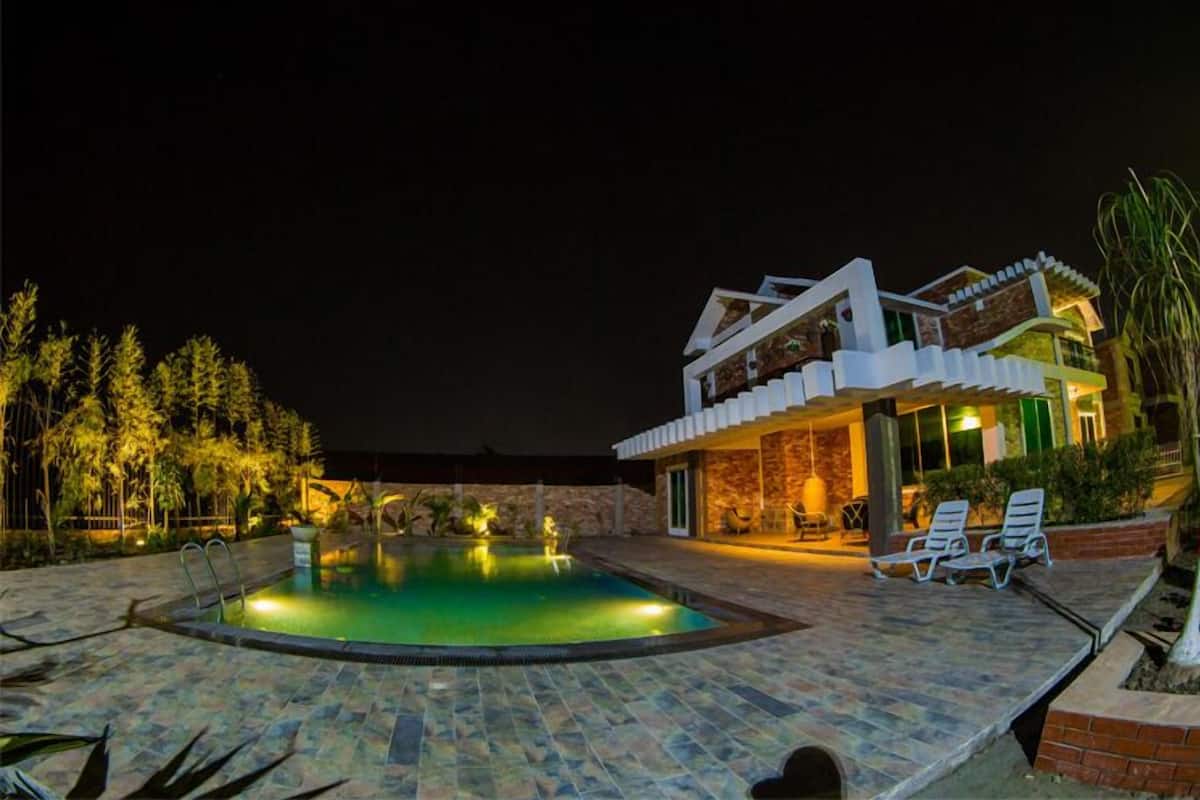 A modern two-story building with a swimming pool and outdoor seating area.