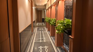 A hallway with patterned flooring, wooden walls, and potted plants. - JVL By Nexottel (Rajkot)