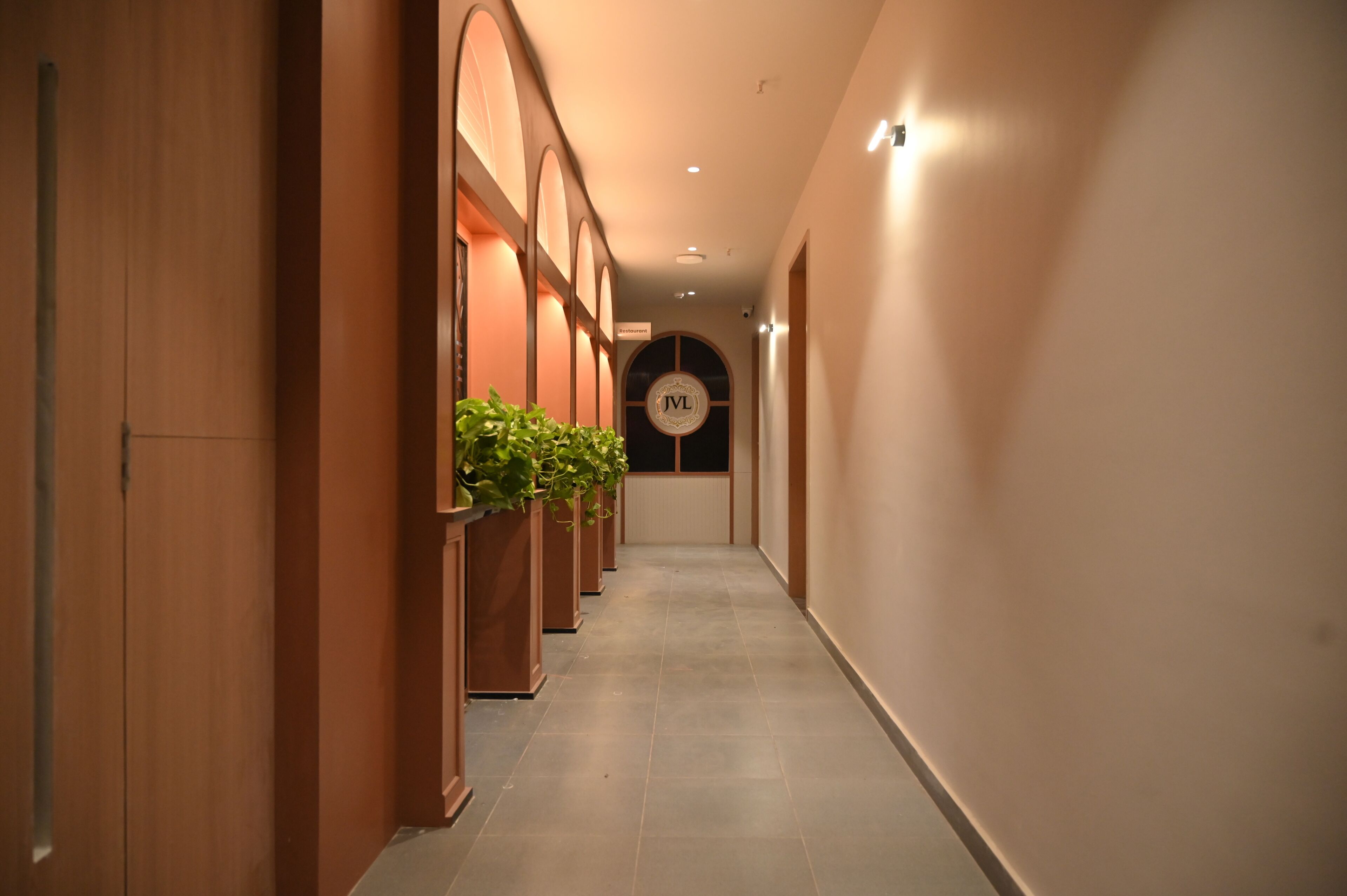A hallway with wooden paneling, potted plants, and a sign with 'JVL' on the wall.