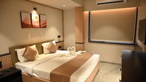 A hotel room with a bed, a TV, a window, and a wall-mounted artwork. - JVL By Nexottel (Rajkot)