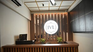 A reception desk with a wooden slat backdrop and a circular logo. - JVL By Nexottel (Rajkot)