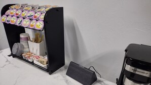 Une machine à café et un distributeur de capsules de café sont posés sur un plan de travail en marbre.