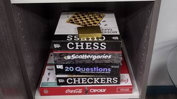 A shelf with a potted plant, chess, and board games.