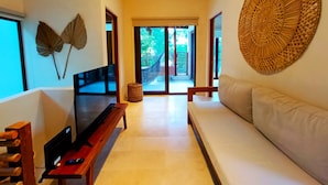 Un salon moderne avec un canapé, un banc en bois, un téléviseur et un ventilateur de plafond.
