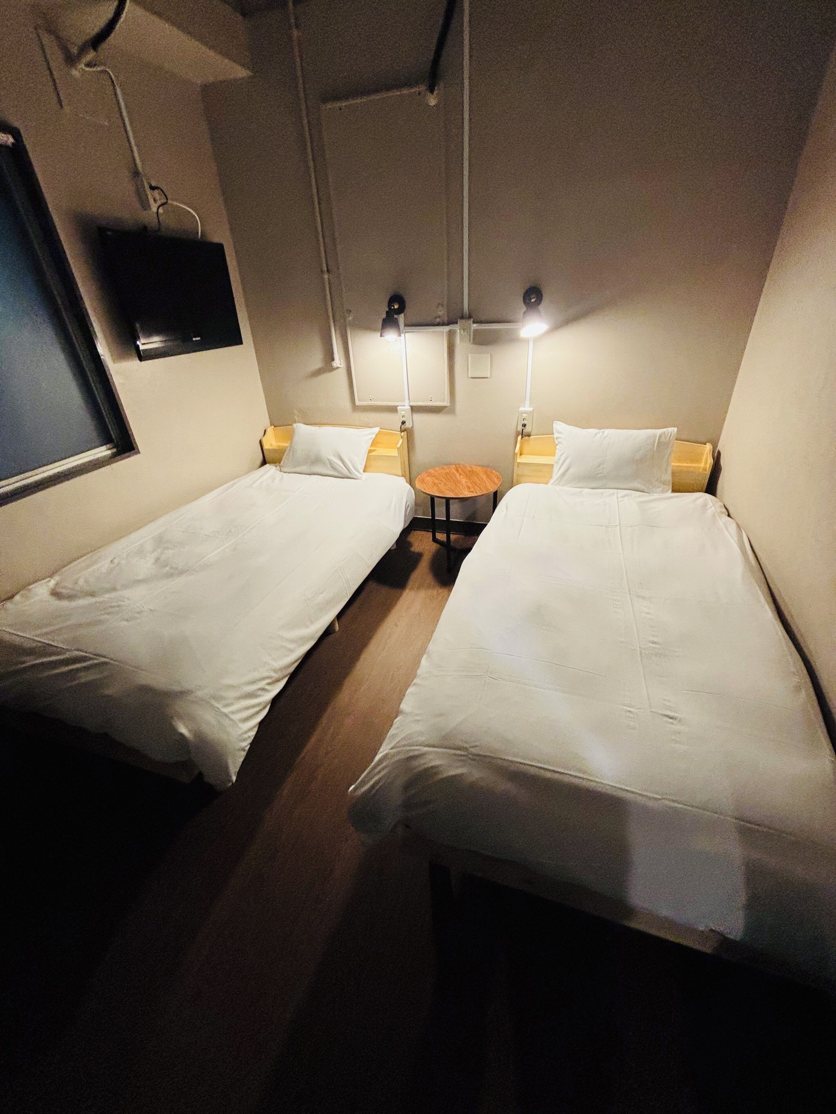 A room with two single beds, a small wooden table, and bedside lamps.
