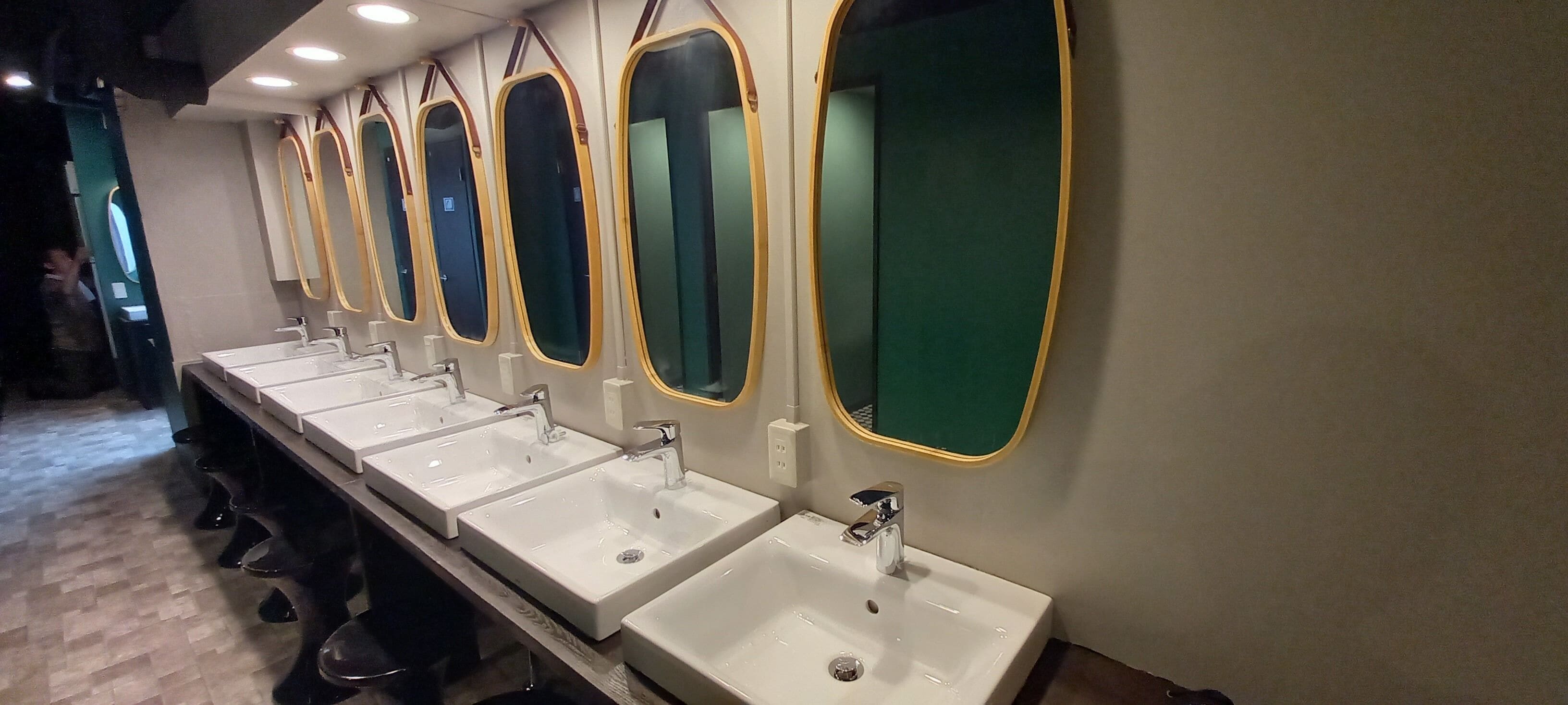 A row of sinks with mirrors and a wooden floor.