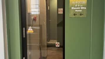 A hotel entrance with a green door, a sign indicating the hotel name, and directional arrows.