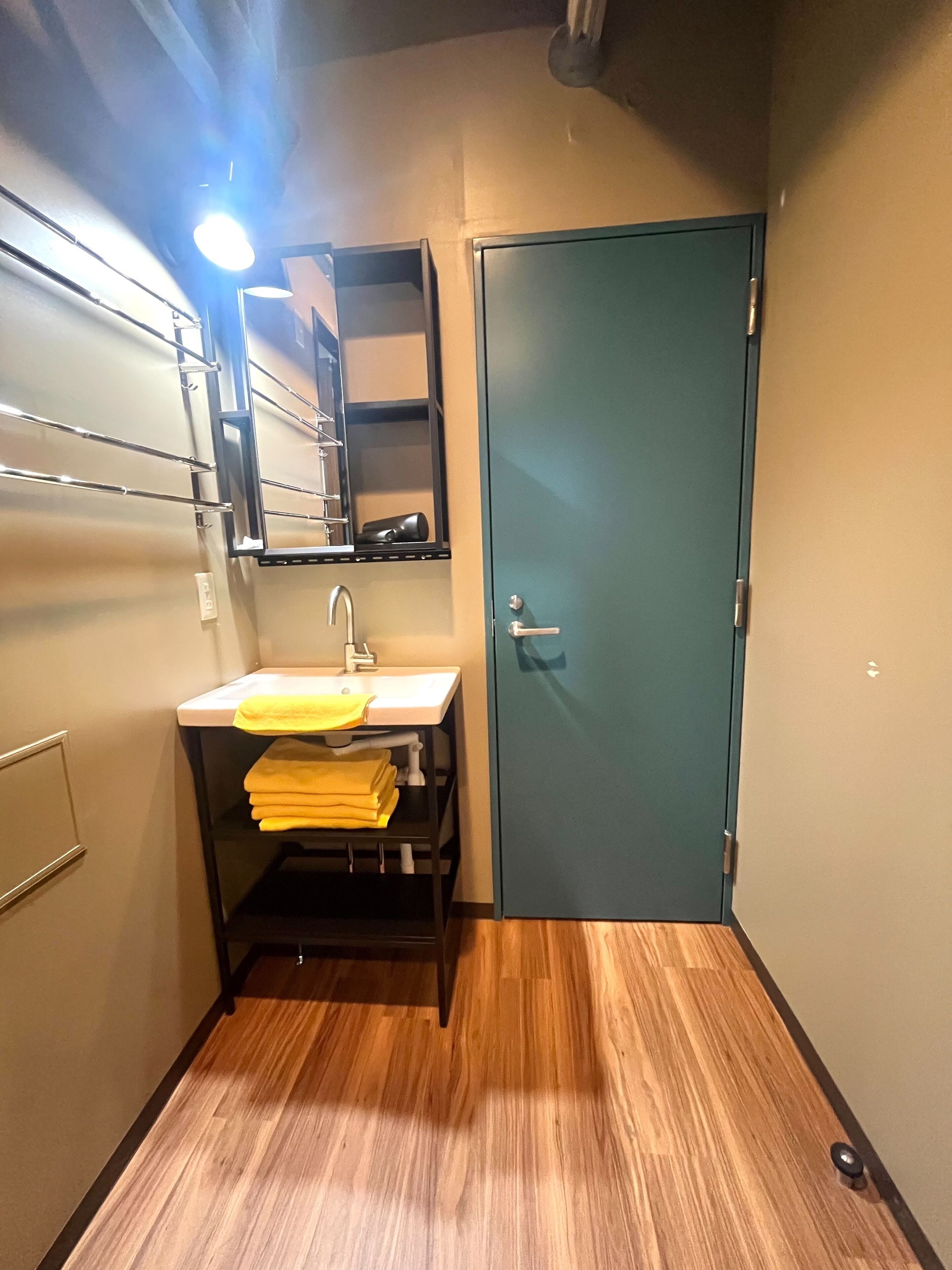 Un baño pequeño con lavamanos, espejo, toallero y puerta.