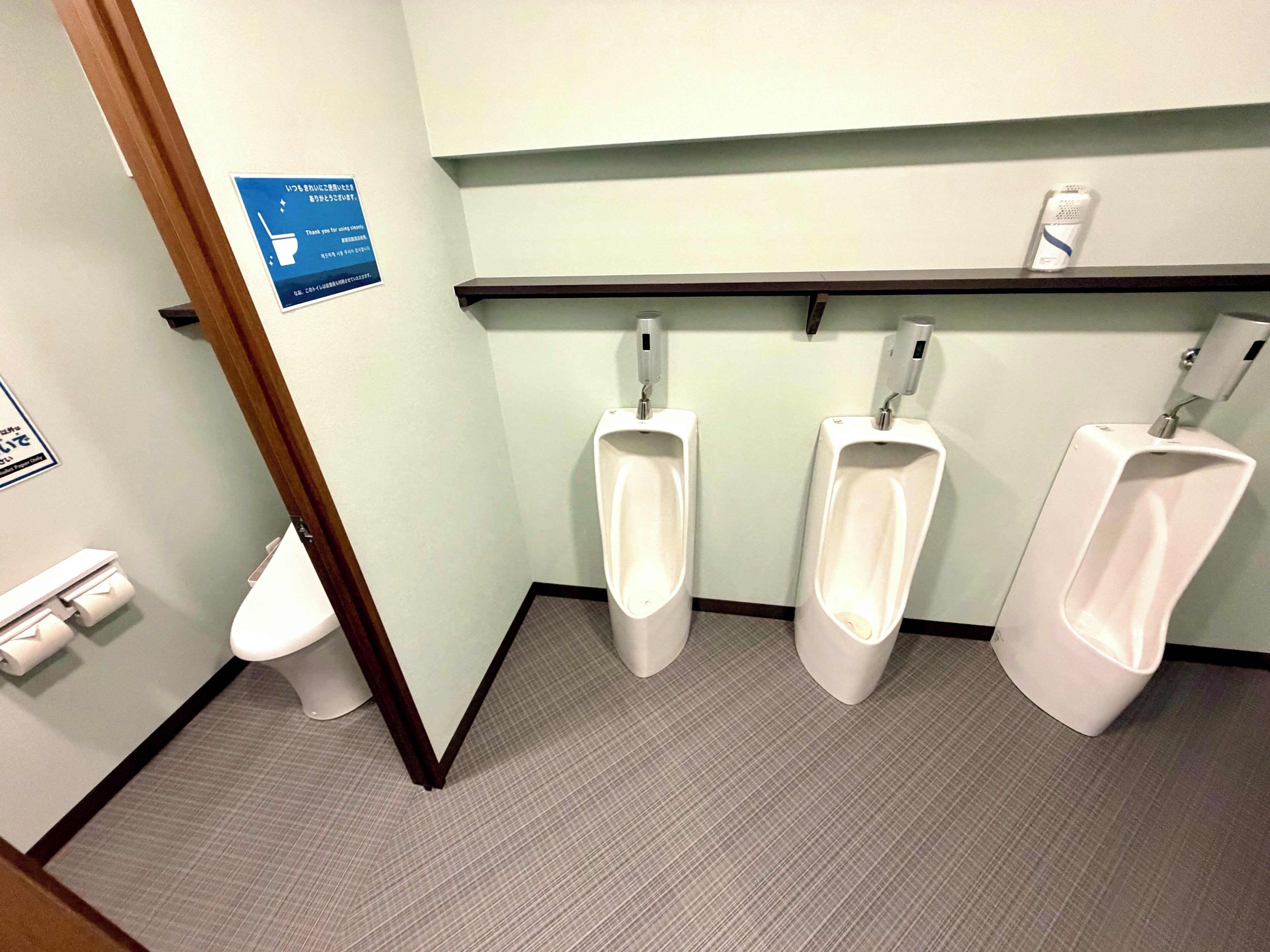 Baño de hombres con orinales, inodoro y secamanos.