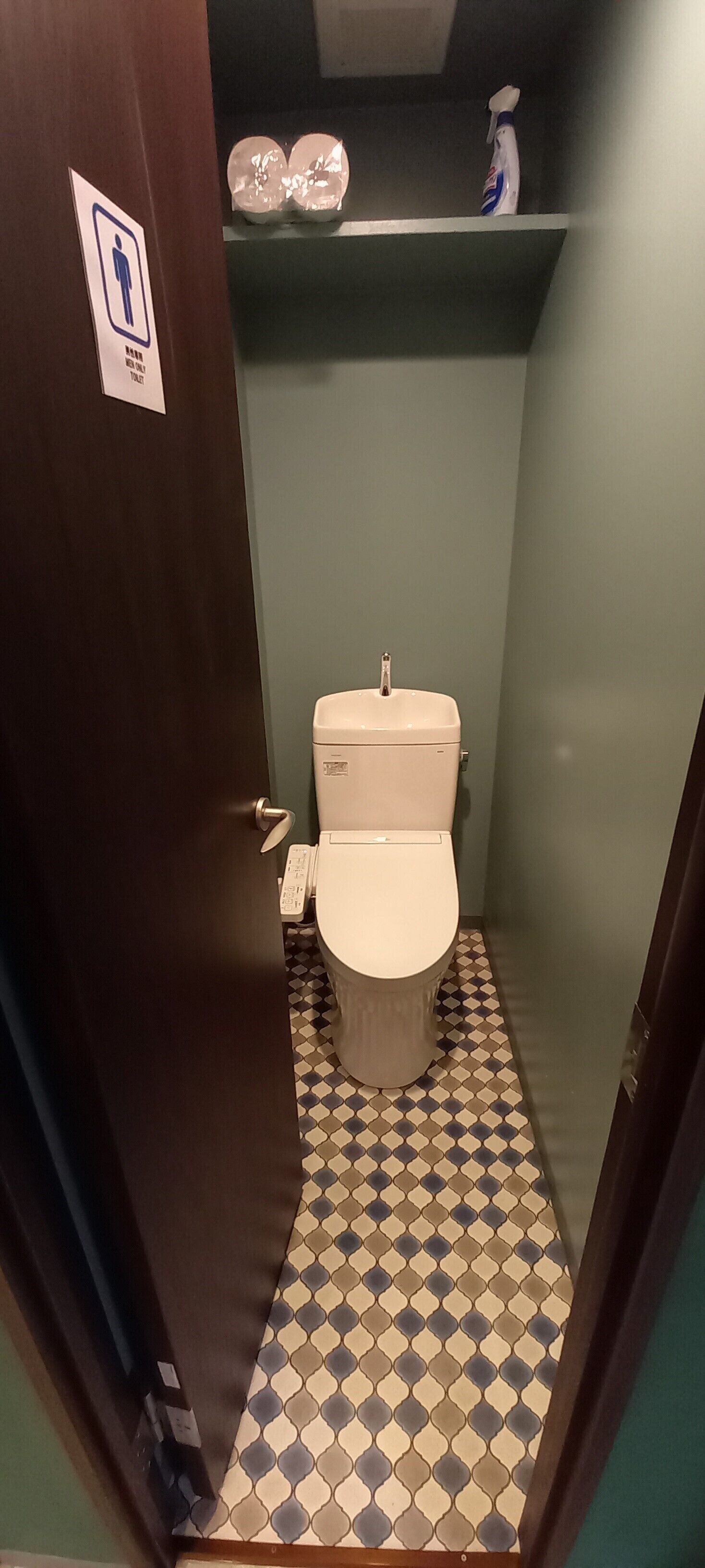 Un baño pequeño con inodoro, un estante sobre el inodoro y un suelo estampado.