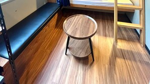 A compact room with a bunk bed, a small round table, and a bench.