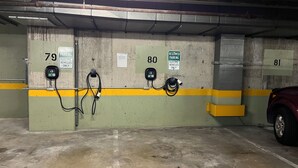 Een parkeergarage met gereserveerde parkeerplaatsen 79 en 80 voor elektrische voertuigen, aangeduid met borden en oplaadpunten.