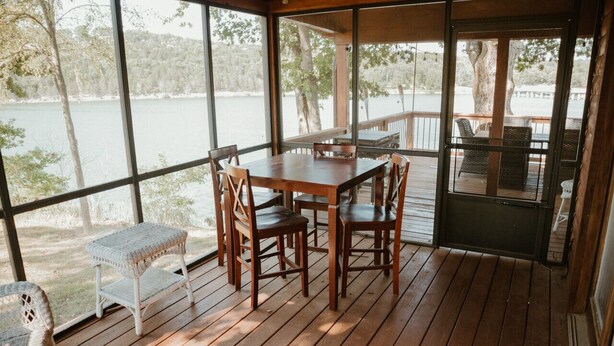 Une terrasse en bois avec une table et des chaises, donnant sur un lac.