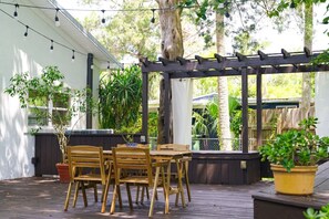 An outdoor patio with wooden furniture, string lights, and potted plants. - Villa Solano| Holiday deals, book now! (Downtown St. Augustine)