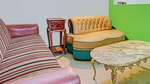 A room with a striped sofa, a tufted sofa, a small wooden side table, and a marble coffee table. - OYO 91599 Penginapan Mutiara Madiun (Jiwan)