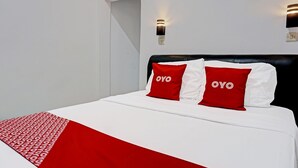 A bed with white bedding and two red pillows with the word "OYO" on them. - OYO 91599 Penginapan Mutiara Madiun (Jiwan)
