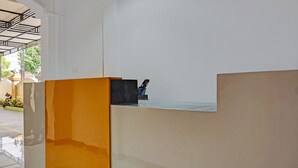 A reception area with a modern design, featuring a reception desk and a seating area. - OYO 91599 Penginapan Mutiara Madiun (Jiwan)