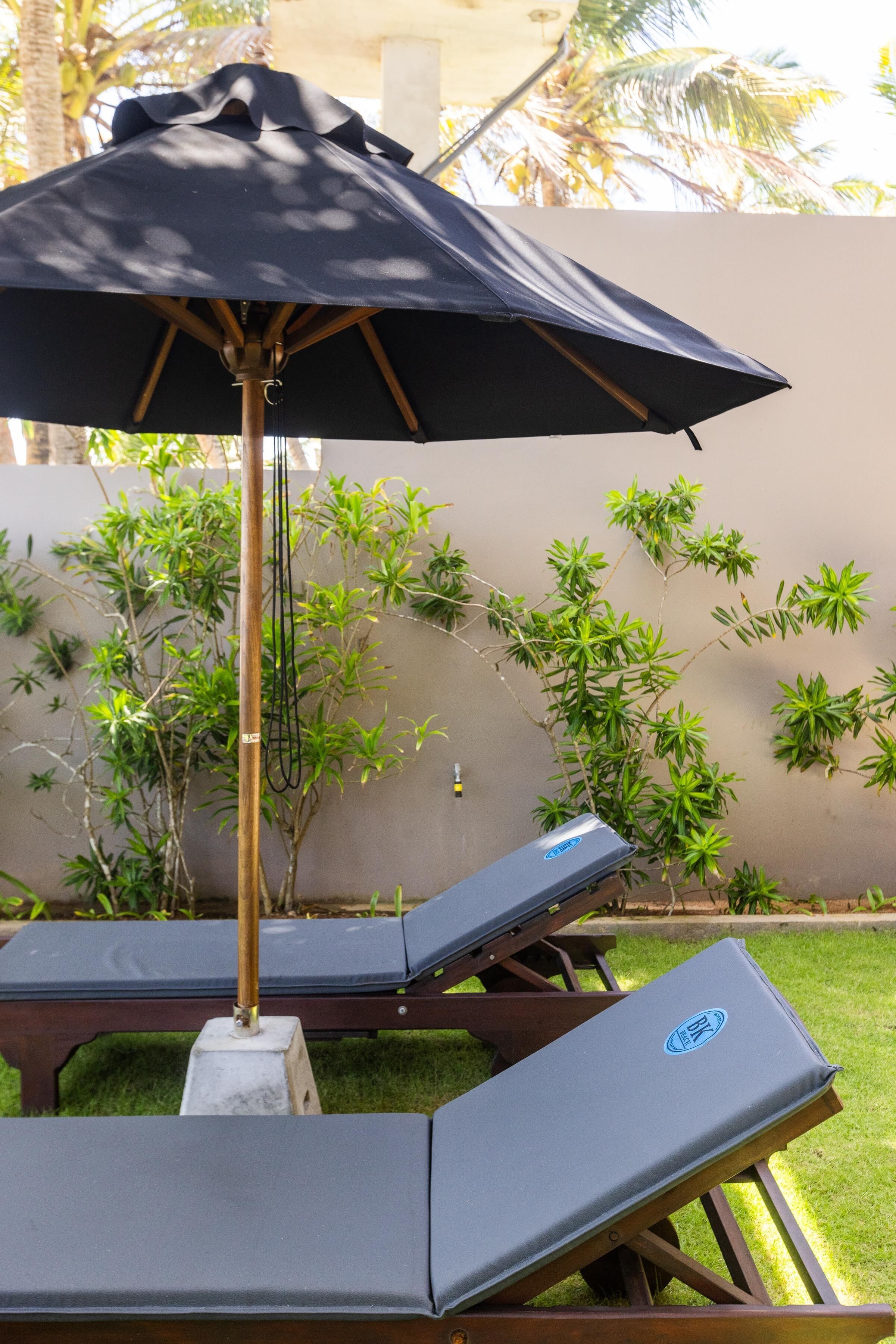 Zona de piscina con sillones de descanso y una sombrilla grande.