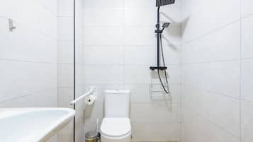 Un baño pequeño y moderno con inodoro blanco, cabezal de ducha y bañera blanca.