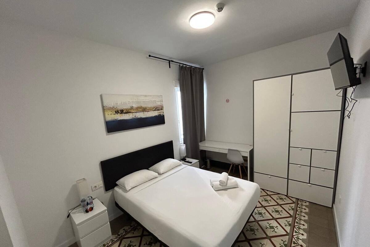 Une chambre d’hôtel avec un lit, un bureau, une télévision et une armoire.
