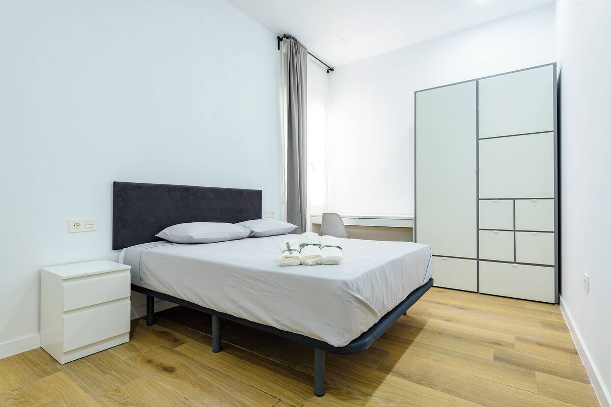 Une chambre à coucher avec un lit, une table de chevet et une armoire.