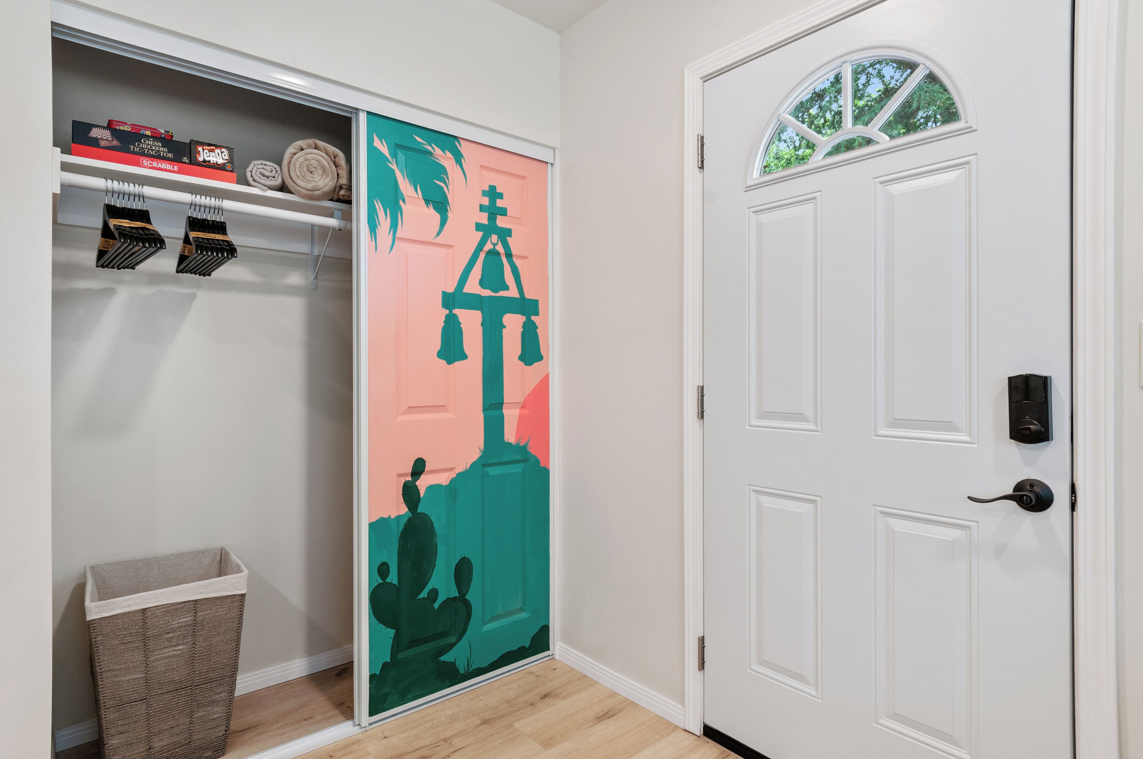 A hallway with a white door, a closet with shelves, and a trash bin.
