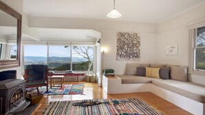 Ein gemütliches Wohnzimmer mit Kamin, einer Couch und einem großen Fenster mit schöner Aussicht.