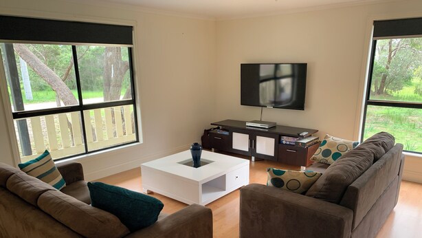 Een moderne woonkamer met twee banken, een salontafel en een tv op een dressoir.
