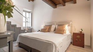 Un dormitorio con una cama grande, una mesita de noche, un aparador y una escalera.
