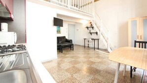 Une cuisine équipée d’une cuisinière à gaz, une table à manger, un canapé et un escalier menant à un niveau supérieur.