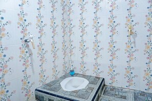 Un baño con baldosas de estampado floral, un inodoro y un secamanos.