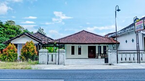 A traditional building with a tiled roof, a gated entrance, and a signboard.