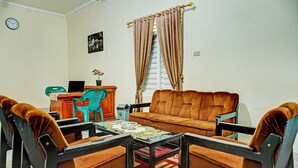 A living room with a sofa, two armchairs, a coffee table, and a small table with a laptop.