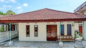 A building with a tiled roof, a wooden bench, and a sign that reads "BUKA".