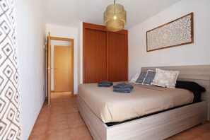 Ein Schlafzimmer mit einem Bett, einem Holzschrank, einer Hängelampe und einer Wanddekoration.