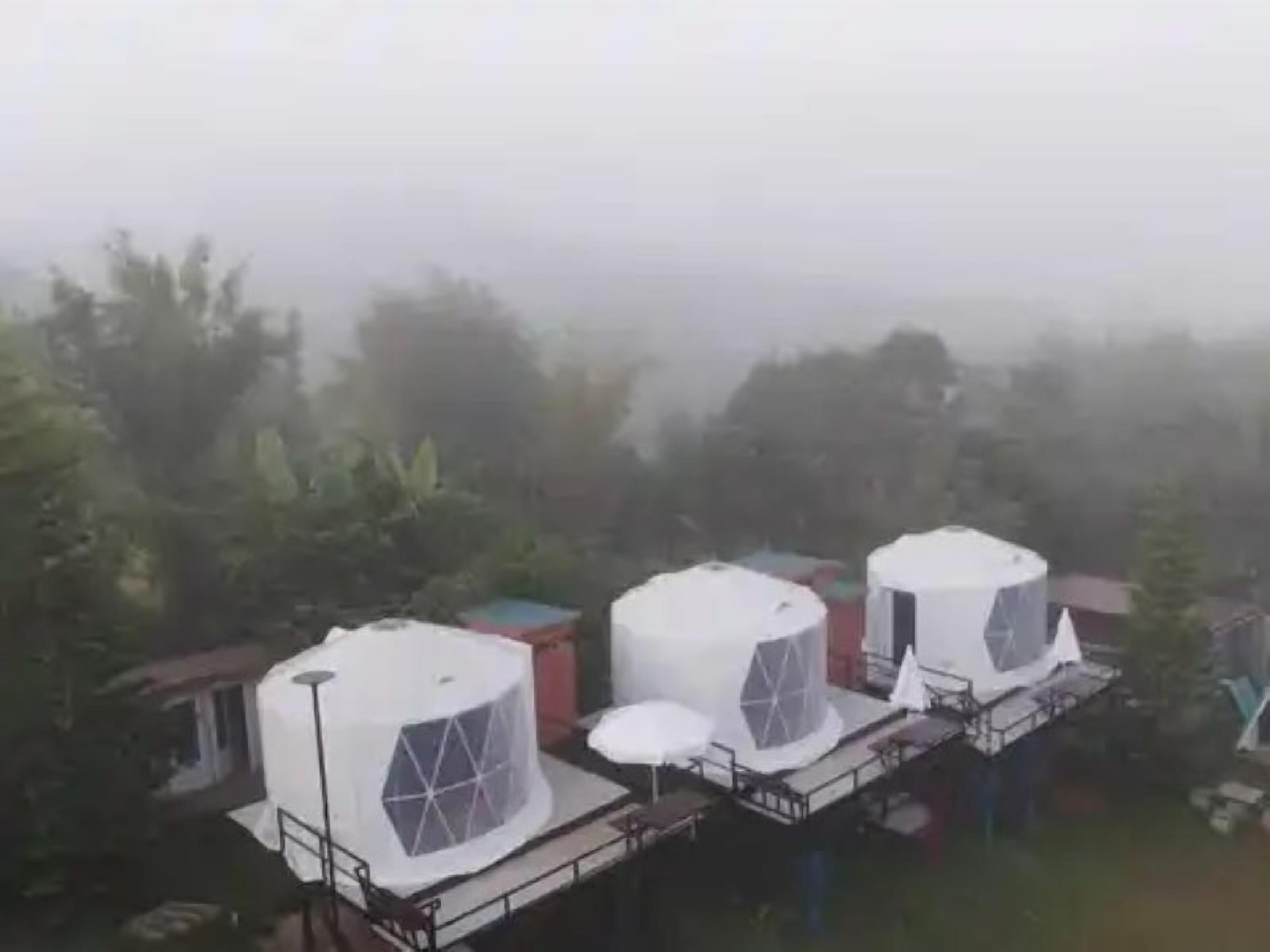 A series of dome-shaped structures with transparent sections, likely part of a resort or hotel complex, surrounded by greenery.