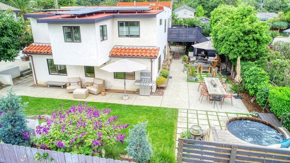 Een tweelaags huis met een patio, compleet met tuinmeubilair, een barbecue en een jacuzzi.