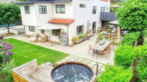 A modern house with a patio, outdoor seating, a hot tub, and a well-maintained garden. - Hermes Haven Beach House - w/ Hot Tub, Blocks to beach (Encinitas)