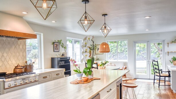 A modern kitchen with a large island, pendant lights, and a view of the outdoors. - Hermes Haven Beach House - w/ Hot Tub, Blocks to beach (Encinitas)