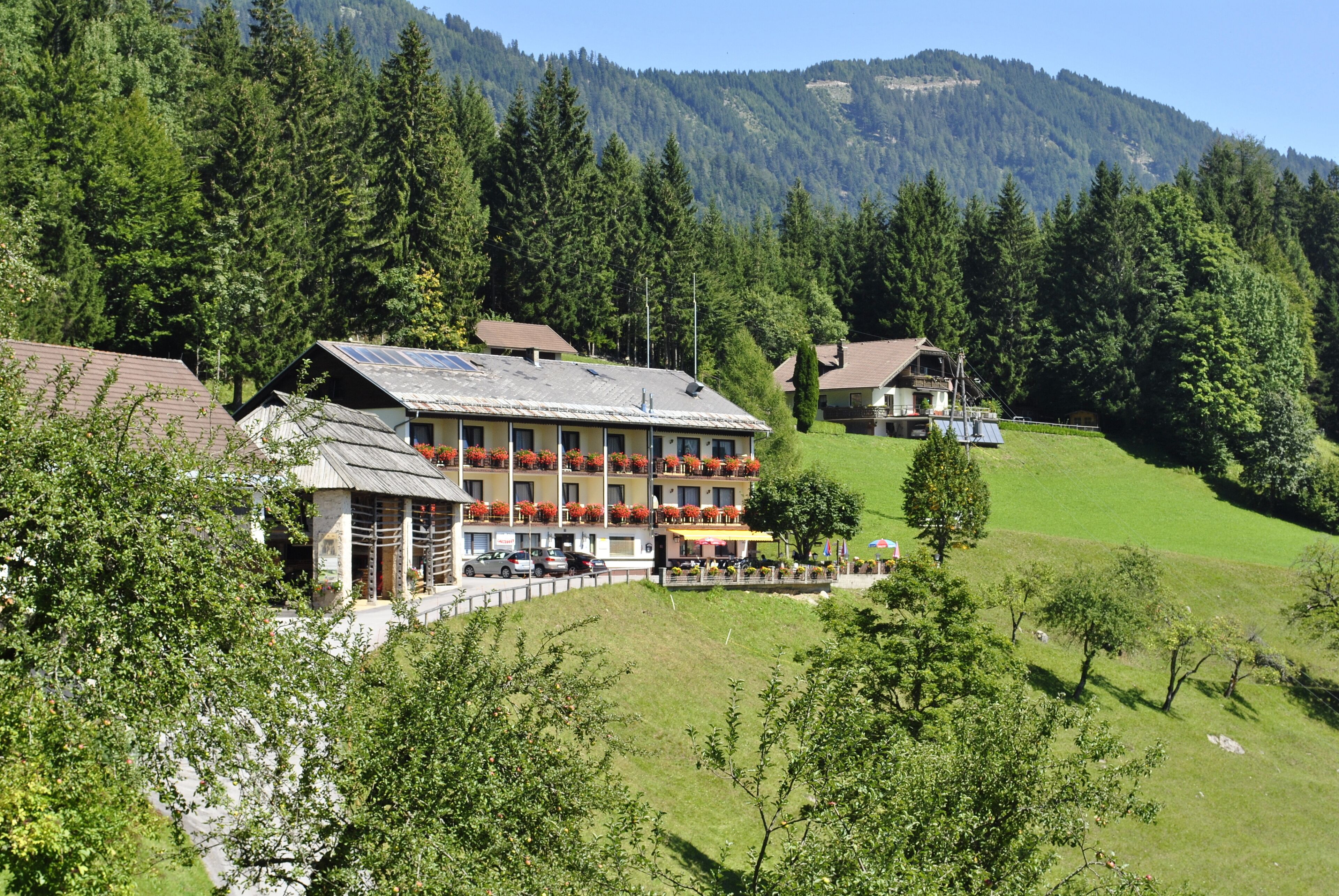 Ein Hotel mit mehreren Etagen, Außenbereich mit roten Blumen und einer Bergkulisse.