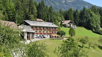 Ein Hotel mit mehreren Etagen, Außenbereich mit roten Blumen und einer Bergkulisse.