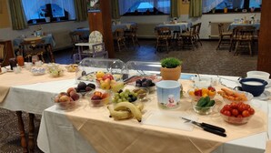 A buffet table with various fruits and vegetables, a cutting board, and a knife. - Bed&Breakfast Lausegger (Ferlach)